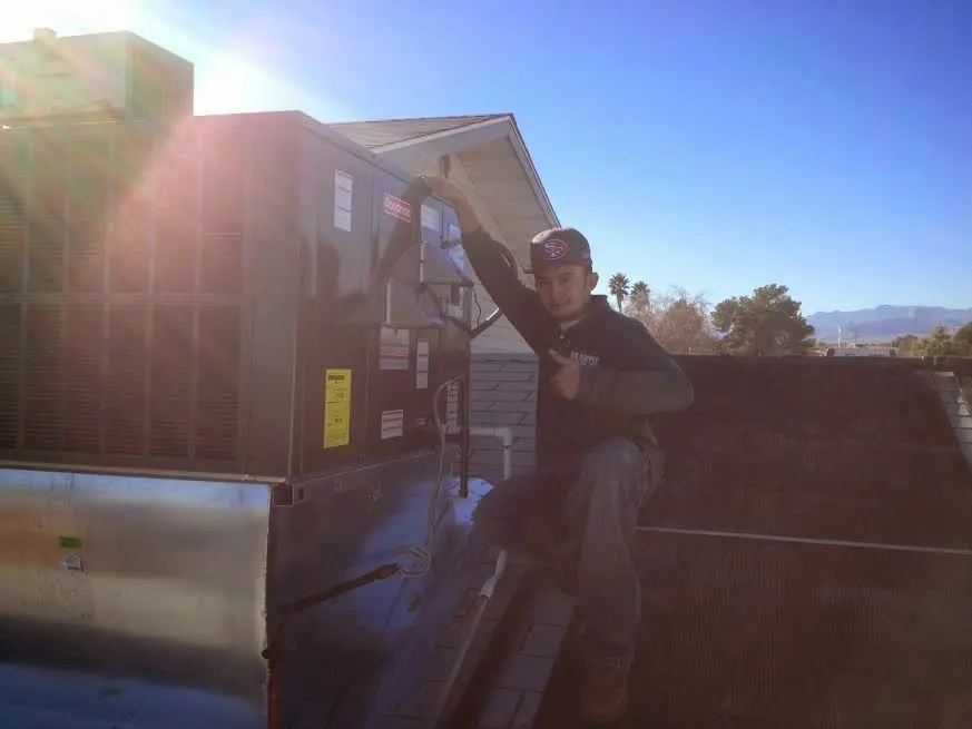 HVAC technician performing AC Tune-Up on a rooftop unit in Rusk